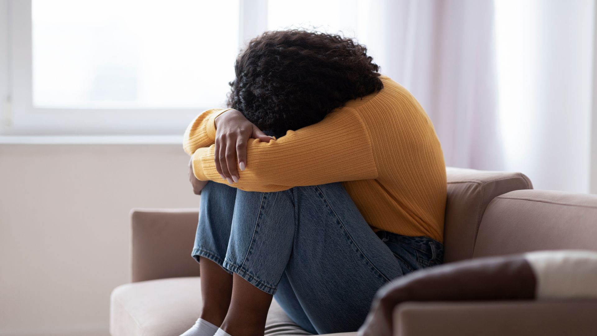 Woman in distress, hugging her knees to her chest with her head buried