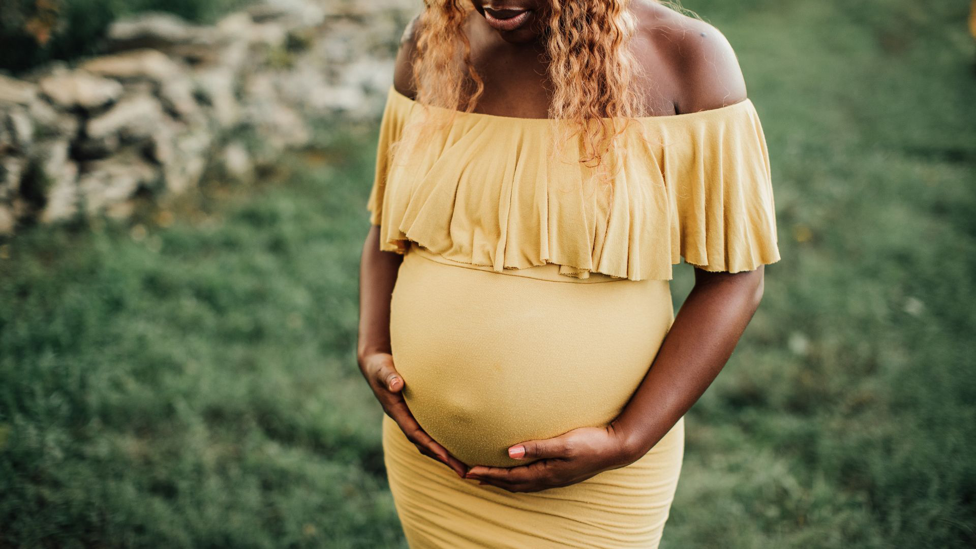 Black pregnant woman cradling her stomach