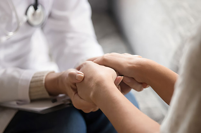 Health professional holding hands of a woman to give comfort