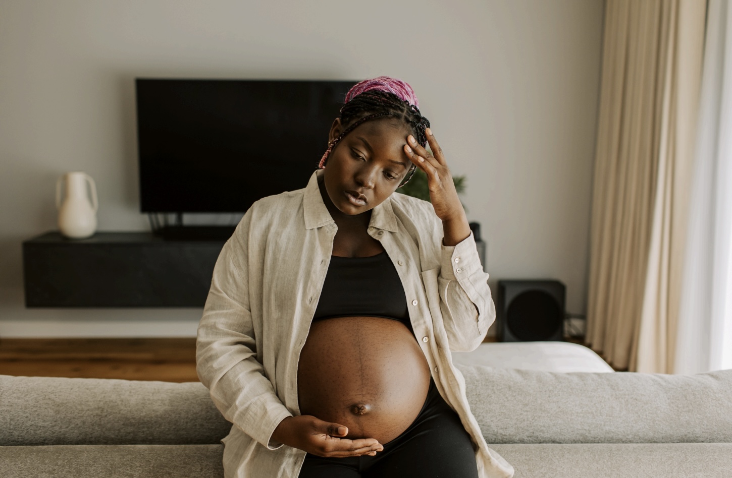 black pregnant woman touching her temple