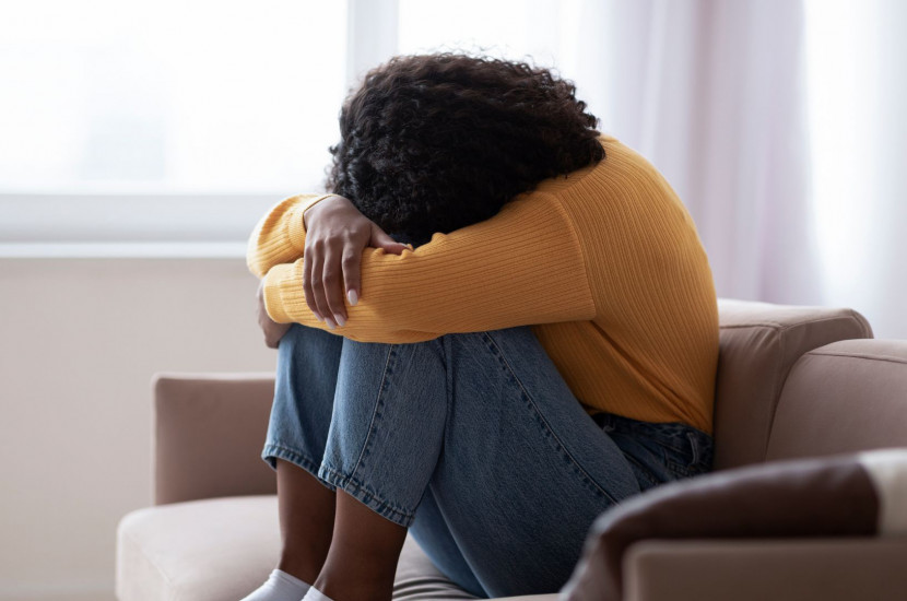 Woman in distress, hugging her knees to her chest with her head buried