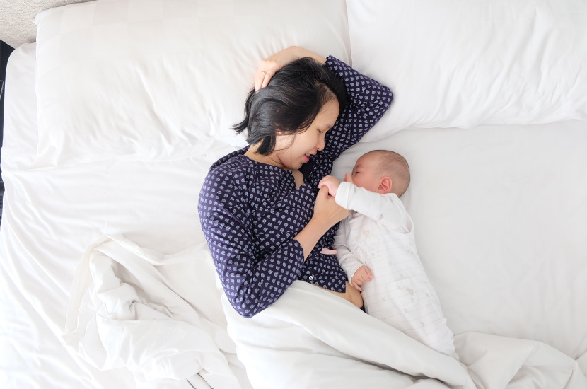 mother laying in bed nursing a baby 