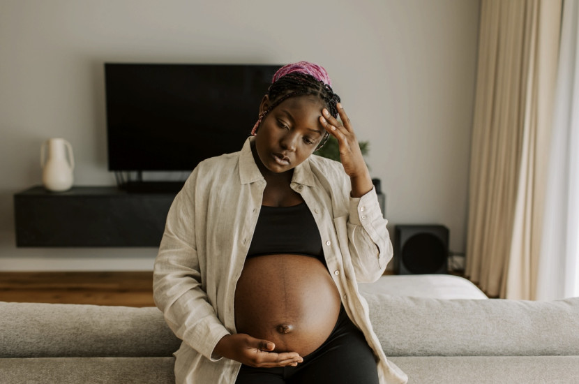 black pregnant woman touching her temple