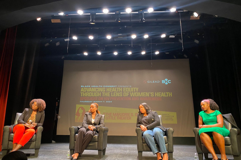 Four Black women sitting in chairs on a stage